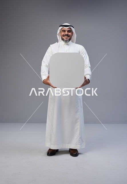رجل سعودي بالزي التقليدي يحمل لوحة بيضاء فارغة