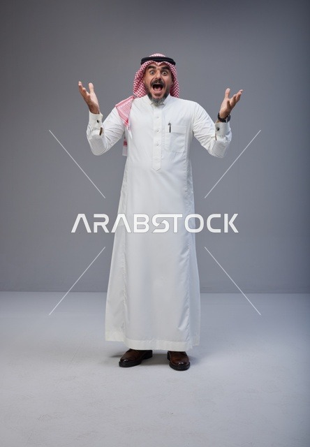 رجل سعودي مندهش بالزي التقليدي أمام خلفية رمادية