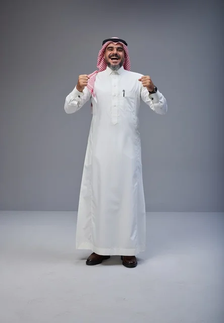 رجل سعودي بالزي التقليدي يحتفل بابتسامة في الاستوديو