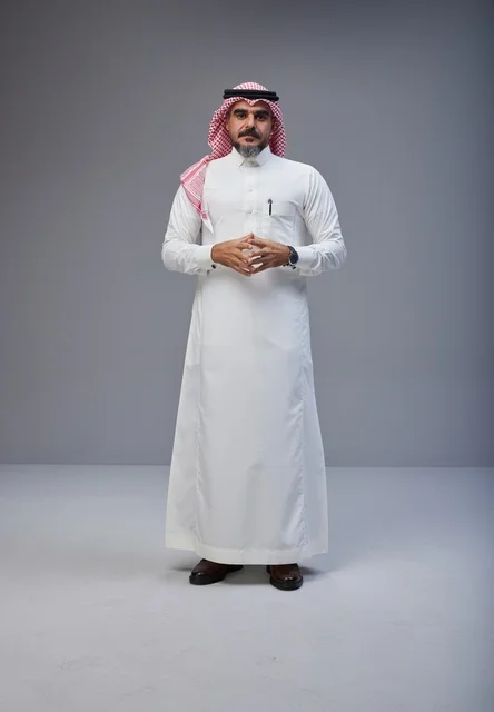رجل سعودي بالزي التقليدي في استوديو بخلفية رمادية