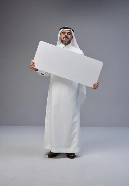 رجل سعودي بالزي التقليدي يحمل لوحة بيضاء فارغة