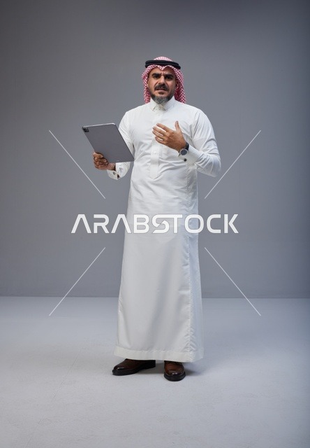 Saudi Man in Traditional Thobe Using Digital Tablet