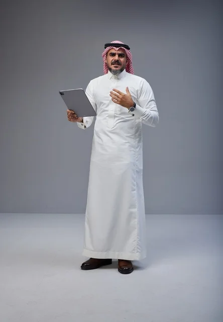 Saudi Man in Traditional Thobe Using Digital Tablet