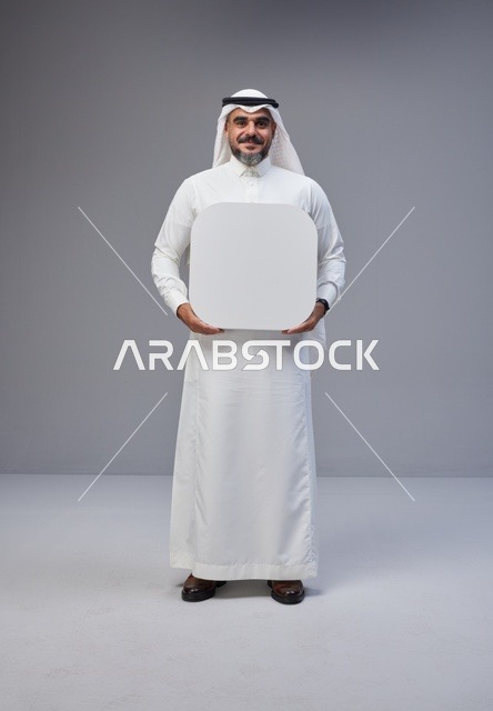 رجل سعودي يحمل لوحة بيضاء فارغة في الاستوديو