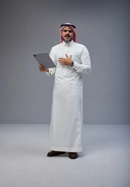 رجل سعودي بالزي التقليدي يستخدم جهاز لوحي في استوديو