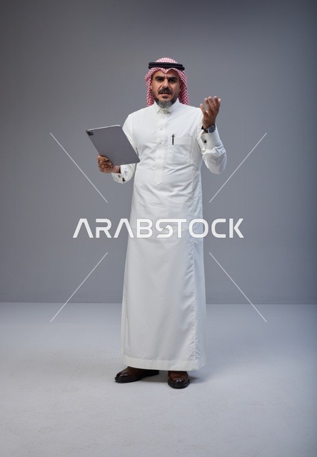 رجل سعودي بالزي التقليدي يستخدم جهاز لوحي