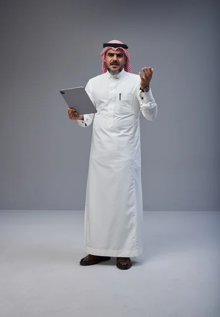 رجل سعودي بالزي التقليدي يستخدم جهاز لوحي