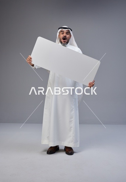 رجل سعودي يرتدي الزي التقليدي يحمل لوحة بيضاء فارغة