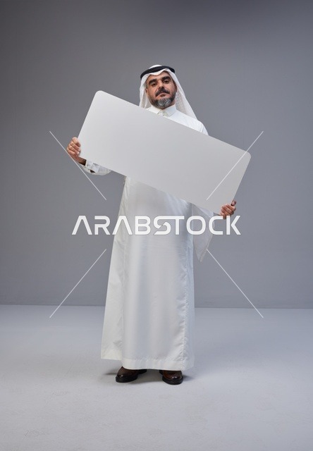 رجل سعودي يحمل لوحة بيضاء فارغة في الاستوديو