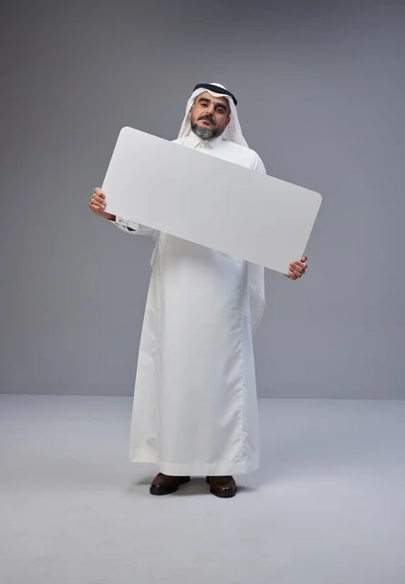 رجل سعودي بالزي التقليدي يحمل لوحة فارغة