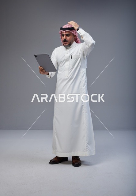 Confused Saudi Man Using Digital Tablet in Studio