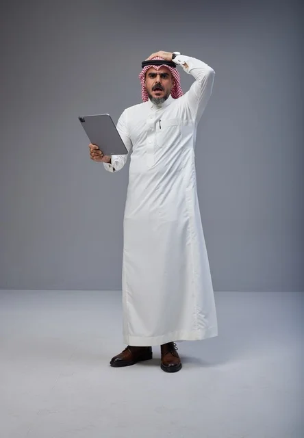 رجل سعودي متفاجئ يحمل جهاز لوحي في الاستوديو