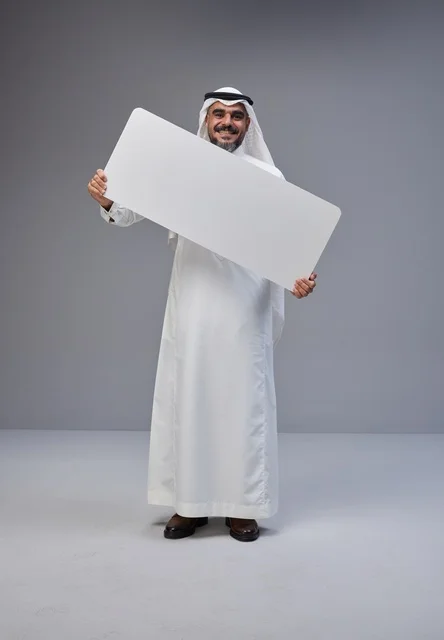 رجل سعودي بالزي التقليدي يحمل لوحة بيضاء فارغة