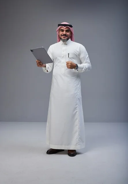 رجل سعودي بالزي التقليدي يحمل جهاز لوحي