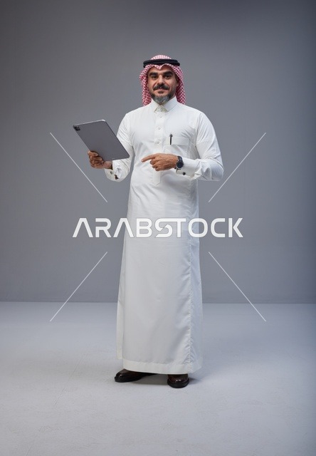 Saudi Man in Traditional Thobe Using Digital Tablet