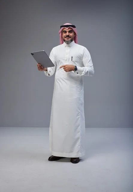 رجل سعودي بالزي التقليدي يستخدم جهاز لوحي