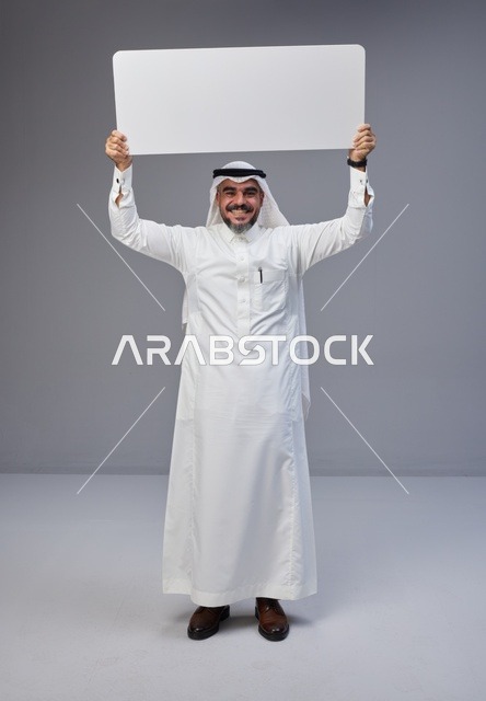 رجل سعودي يحمل لوحة بيضاء فارغة في الاستوديو