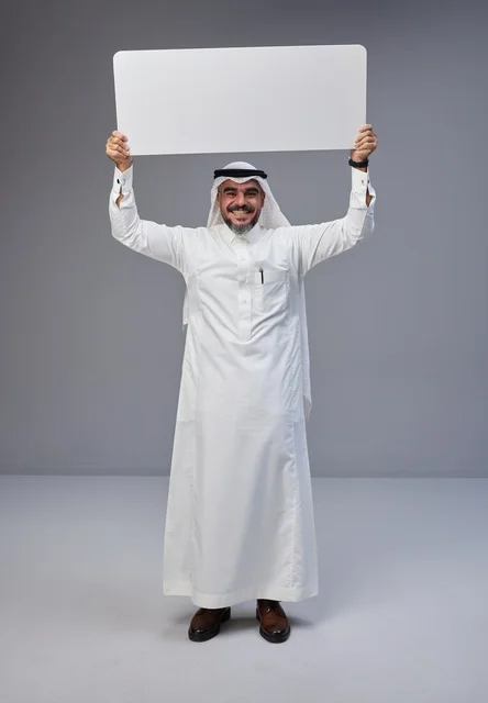 رجل سعودي يحمل لوحة بيضاء فارغة في الاستوديو