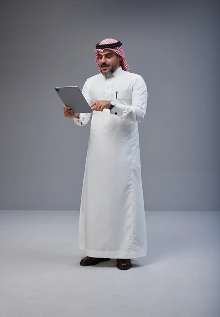 رجل سعودي بالزي التقليدي يستخدم جهاز لوحي في الاستوديو