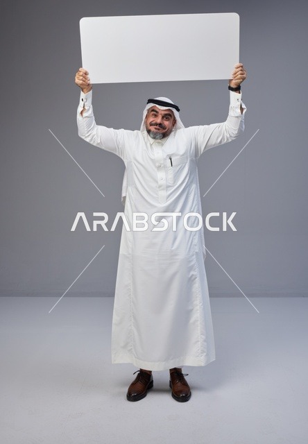 رجل سعودي يحمل لوحة بيضاء فارغة في استوديو