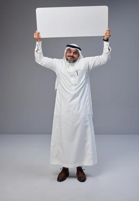 رجل سعودي يحمل لوحة بيضاء فارغة في استوديو