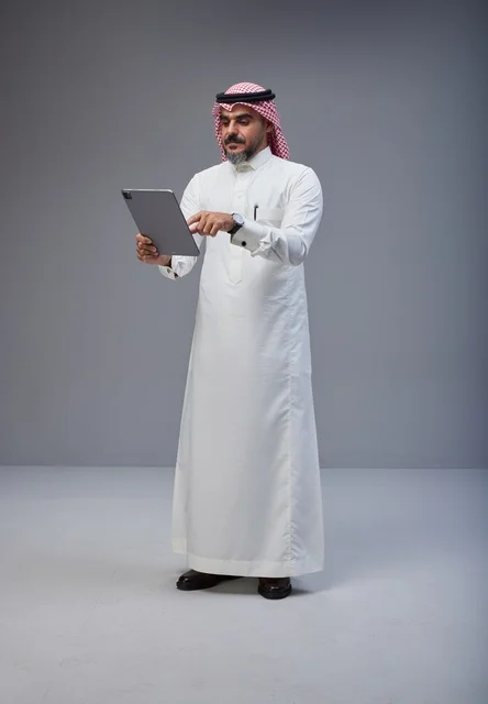 Saudi Man in Traditional Dress Using a Digital Tablet