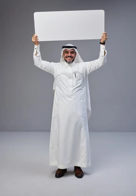رجل سعودي بالزي التقليدي يحمل لوحة بيضاء فارغة