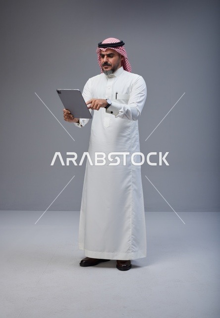 Saudi Man in Traditional Thobe Using Digital Tablet