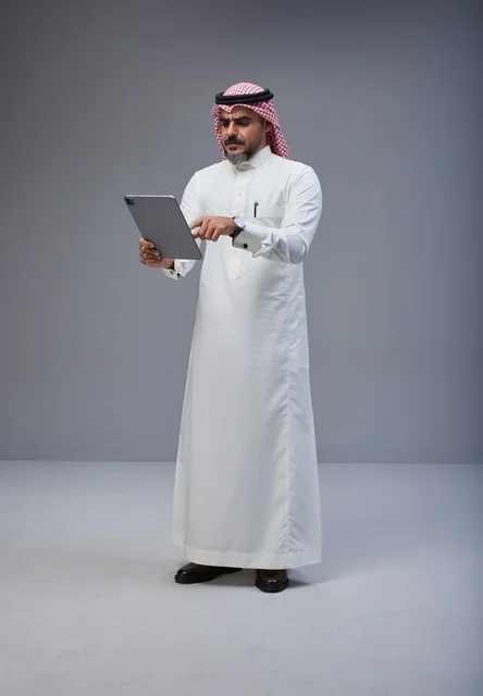 Saudi Man in Traditional Thobe Using Digital Tablet