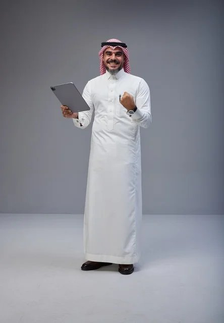 رجل سعودي بالزي التقليدي يحتفل بنجاحه عبر الجهاز اللوحي