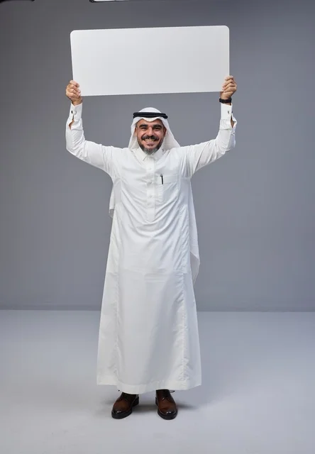 رجل سعودي بالزي التقليدي يحمل لوحة بيضاء فارغة