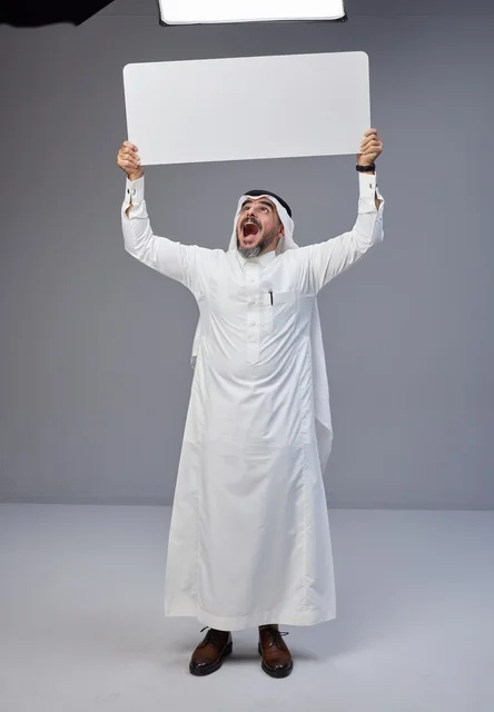رجل سعودي بالزي التقليدي يحمل لوحة بيضاء فارغة