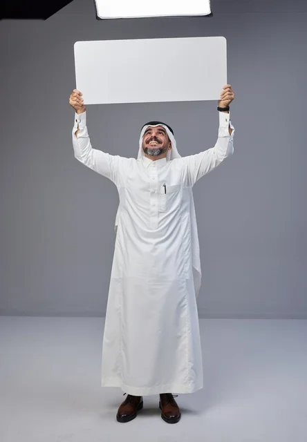 رجل سعودي يحمل لوحة بيضاء فارغة في الاستوديو