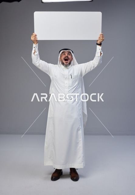رجل سعودي بالزي التقليدي يحمل لوحة بيضاء فارغة
