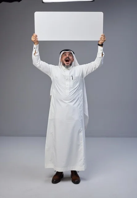 رجل سعودي بالزي التقليدي يحمل لوحة بيضاء فارغة