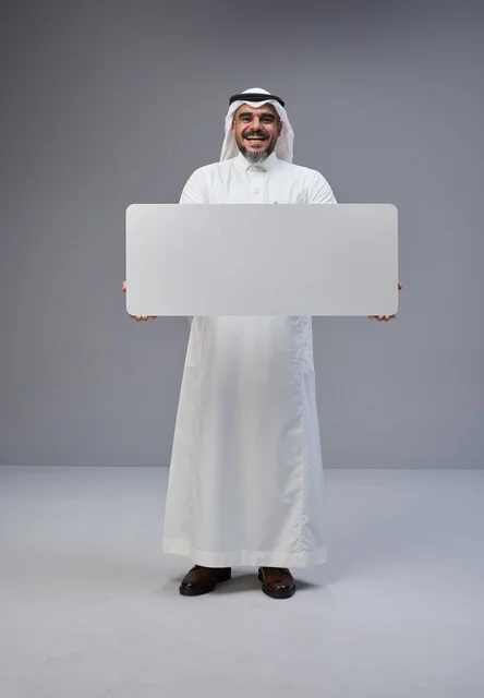 رجل سعودي يحمل لوحة بيضاء فارغة في استوديو
