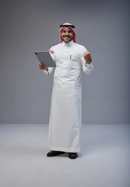 رجل سعودي يستخدم جهاز لوحي ويحتفل بالنجاح
