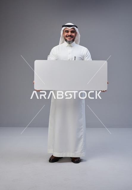 رجل سعودي بالزي التقليدي يحمل لوحة بيضاء فارغة