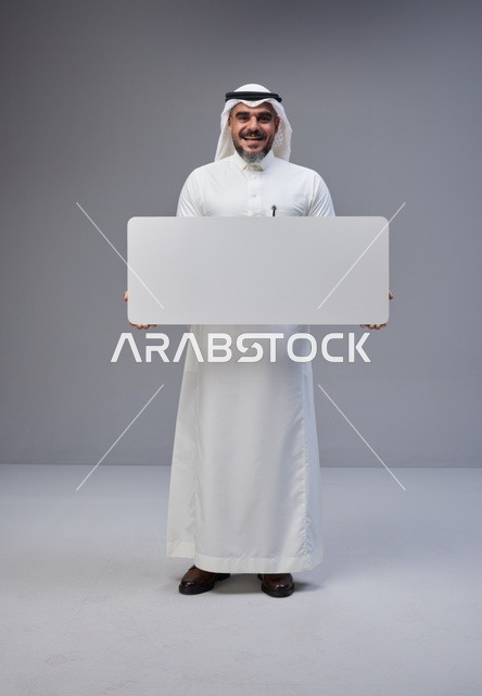 رجل سعودي بالزي التقليدي يحمل لوحة بيضاء فارغة
