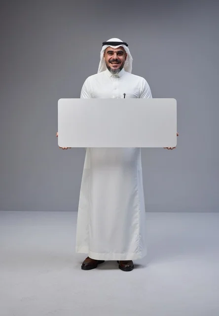رجل سعودي بالزي التقليدي يحمل لوحة بيضاء فارغة