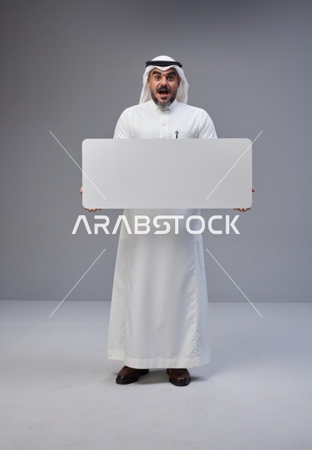 رجل سعودي يحمل لافتة بيضاء فارغة في استوديو