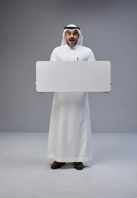 رجل سعودي يحمل لافتة بيضاء فارغة في استوديو
