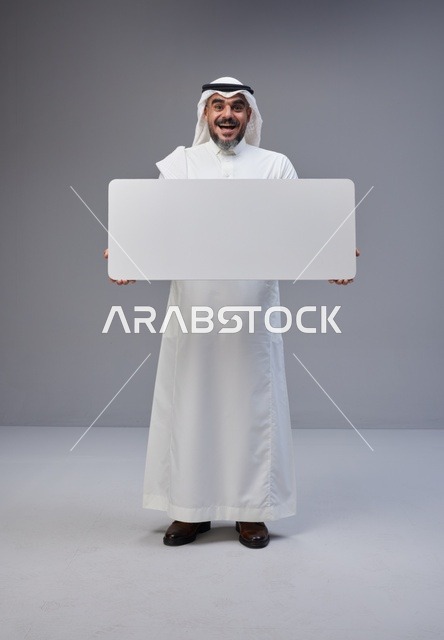 رجل سعودي يحمل لوحة إعلانية فارغة في الاستوديو