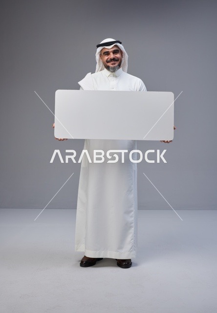 رجل سعودي يحمل لوحة بيضاء فارغة في الاستوديو