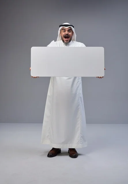 رجل سعودي بالزي التقليدي يحمل لافتة إعلانية بيضاء فارغة