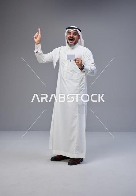 رجل سعودي يحمل بطاقة تعريف فارغة ويشير للأعلى