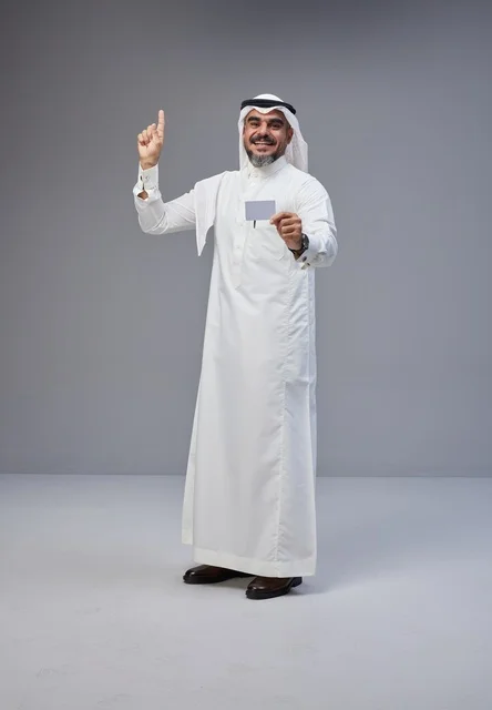 رجل سعودي يحمل بطاقة فارغة ويشير للأعلى خلفية رمادية