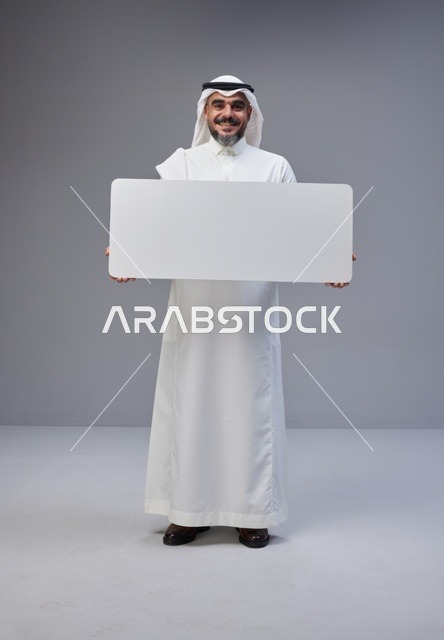 رجل سعودي يحمل لوحة بيضاء فارغة في الاستوديو