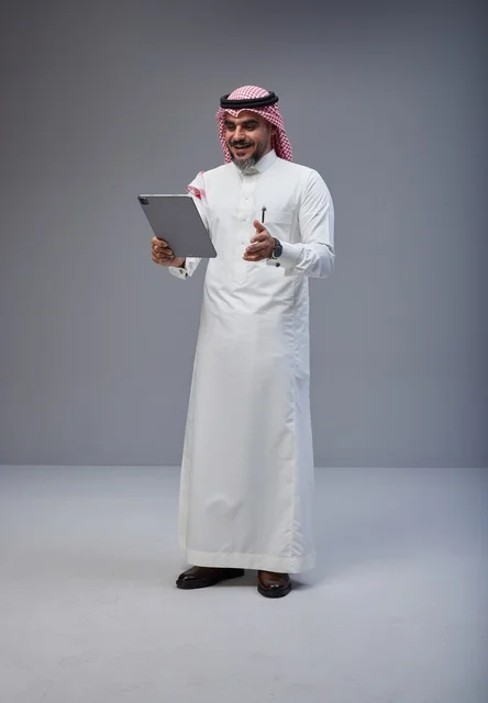 رجل سعودي بالزي التقليدي يستخدم جهاز لوحي في الاستوديو
