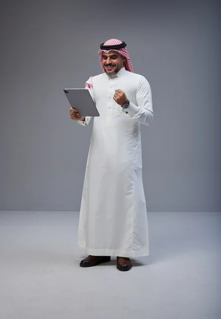 رجل سعودي مع جهاز لوحي يحتفل بالنجاح في الاستوديو